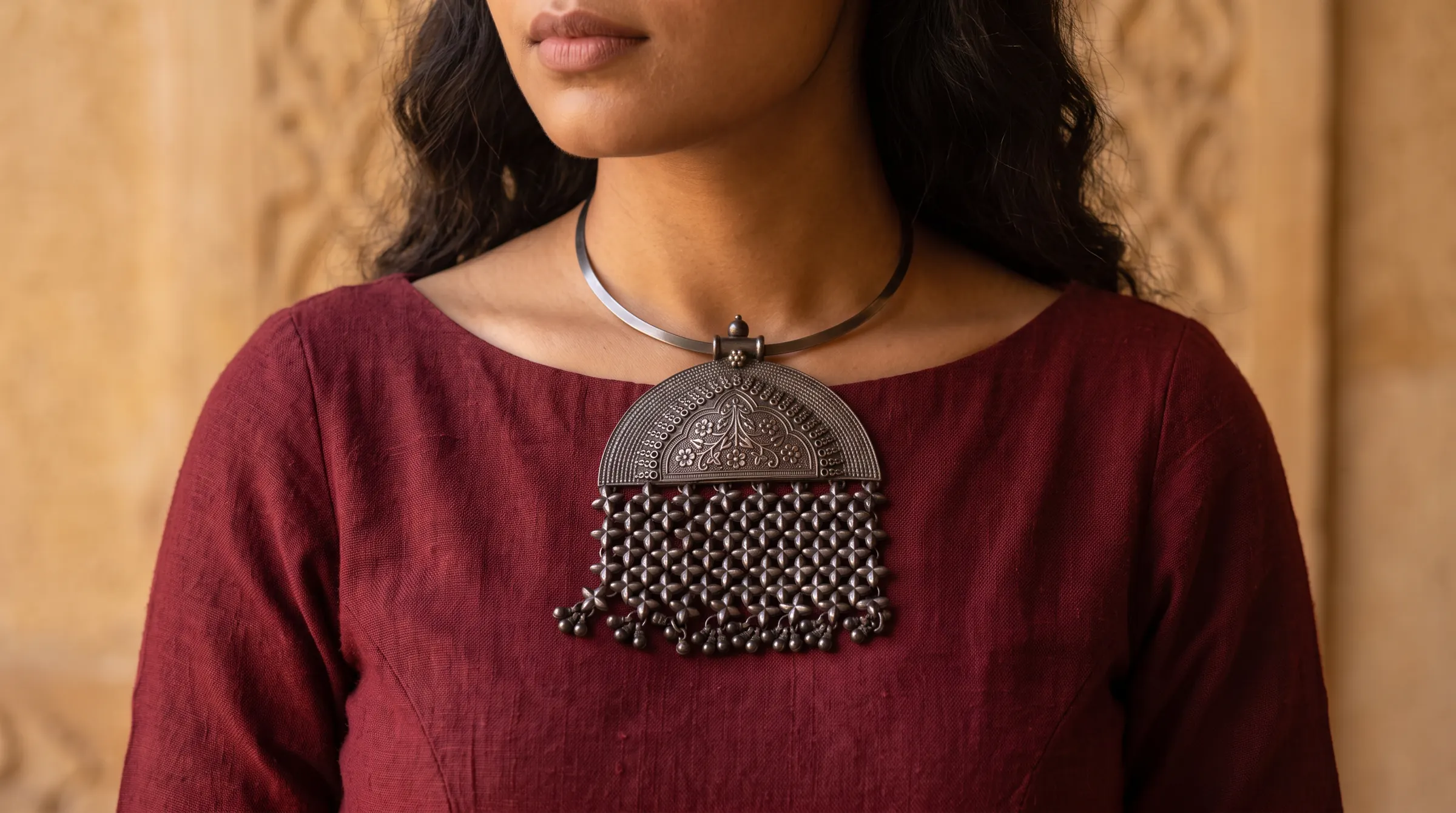 A woman wearing the silver hasli necklace over a maroon handloom top